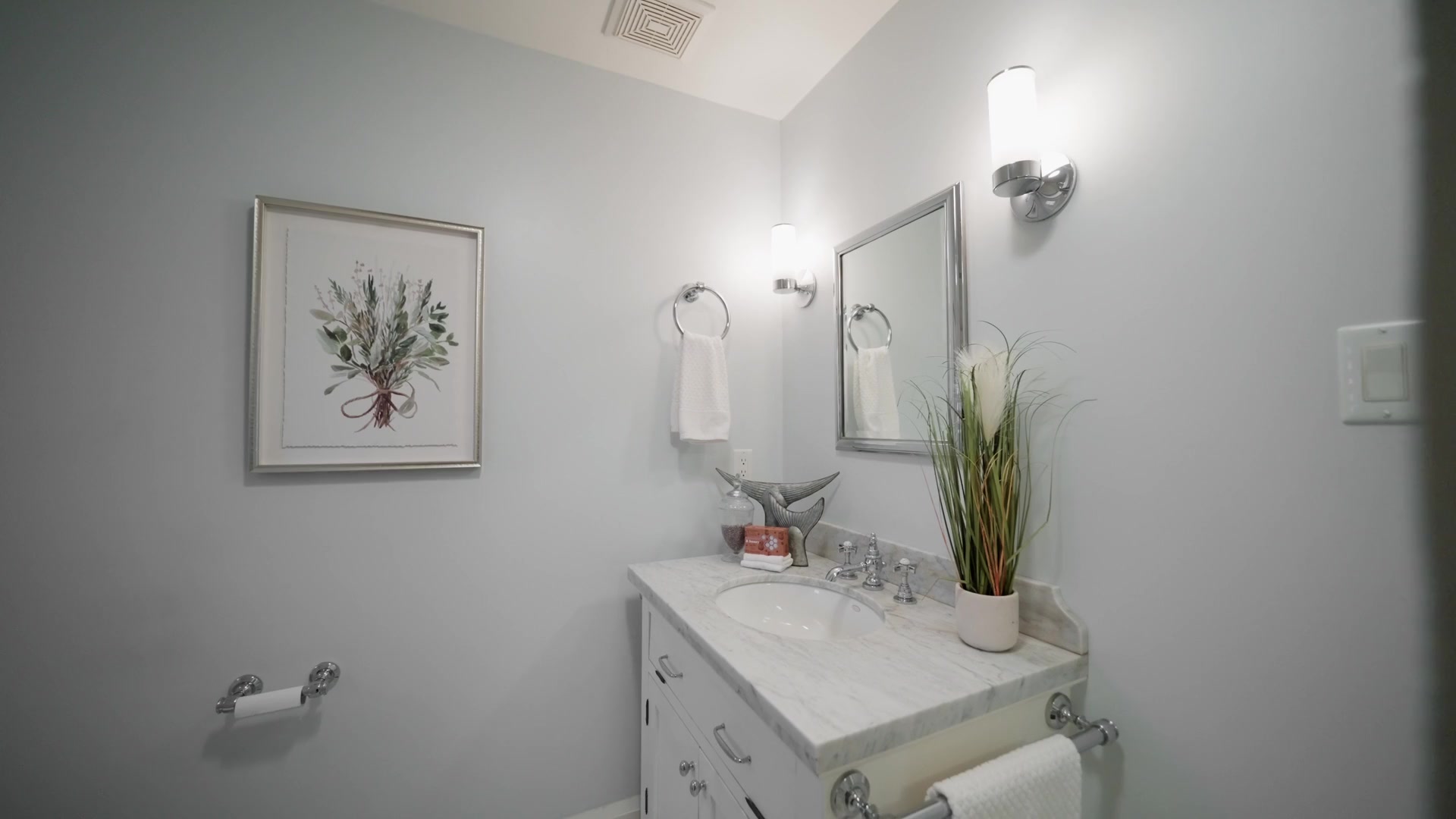 Powder room with marble vanity and chrome sconces